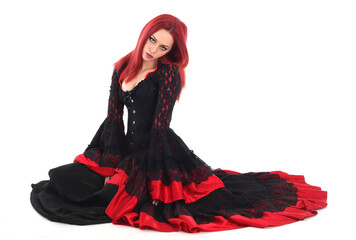 portrait of beautiful red haired woman wearing long black fantasy vampire costume gown, isolated pose on  studio background.