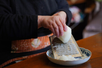 おろし金で大根をおろす女性