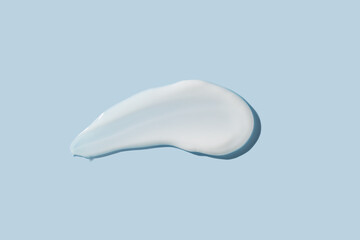 Cosmetic product smear white moisturizing lotion isolated on blue, squeezed out and smeared portion of skincare cream product testing.