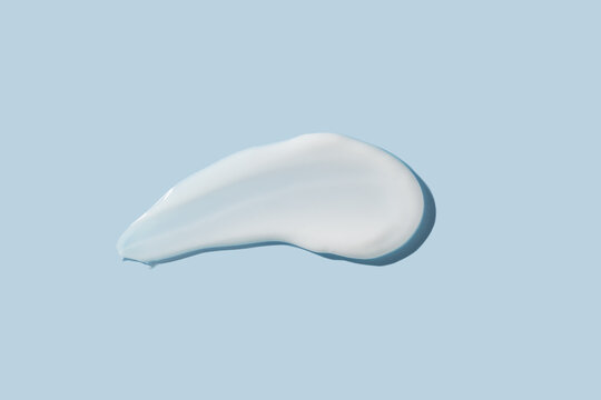 Cosmetic Product Smear White Moisturizing Lotion Isolated On Blue, Squeezed Out And Smeared Portion Of Skincare Cream Product Testing.