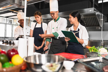 Asia chef teaching Asia woman assistant chef cooking at kitchen background	