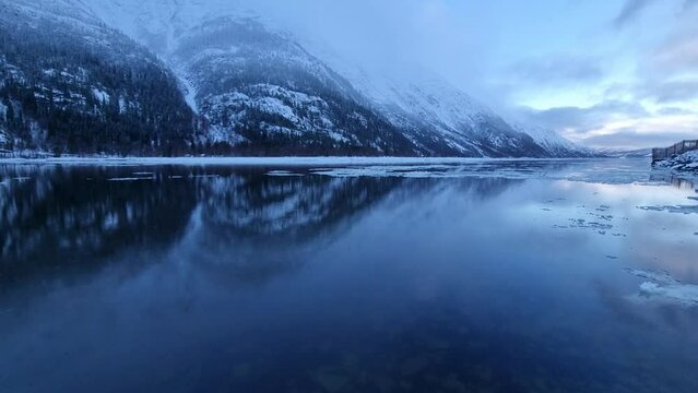floating ice flakes on water with mountain reflection on surface and moving clouds, timelapse video