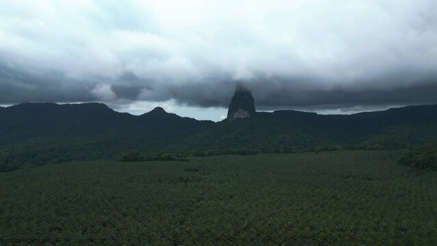 Aerial view rising towards the clouds covered Pico Cao Grande mountain, in Sao Tome