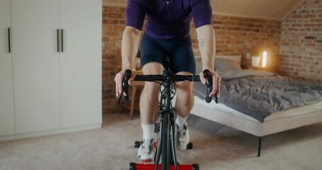 A man in virtual reality glasses, dressed in sportswear, trains on a bicycle simulator in a stylish home interior