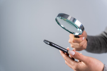 Woman looking at the phone with a magnifying glass