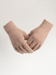 Gloves on an invisible mannequin. Beige gloves on a light gray background studio shot. Women's knitted gloves, isolated.