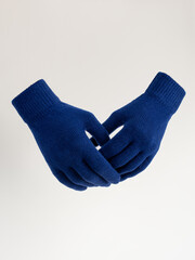 Gloves on an invisible mannequin. Blue gloves on a light gray background studio shot. Women's knitted gloves, isolated.