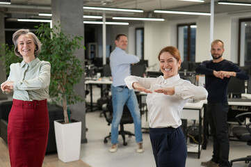 Four office workers warm up during a break. Employees do fitness exercises at the workplace. 