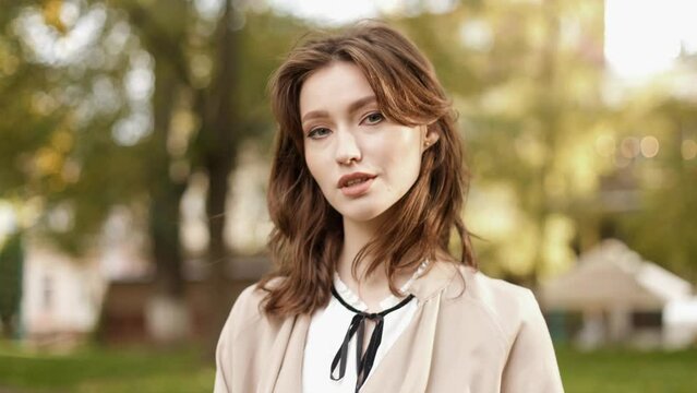 Young elegant woman teacher businesswoman standing in park. Portrait of a female university teacher on the background of an educational institution.
