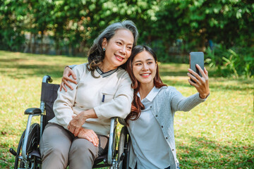 Asian grandmother in wheelchair with daughter is enjoying at the park in the morning