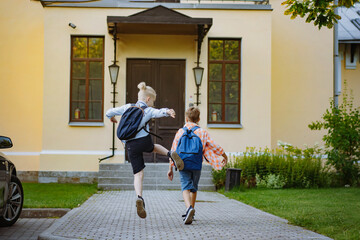 children running to school with backpacks on sunny day. Begining of academic year. Boys by school doorstep - obrazy, fototapety, plakaty