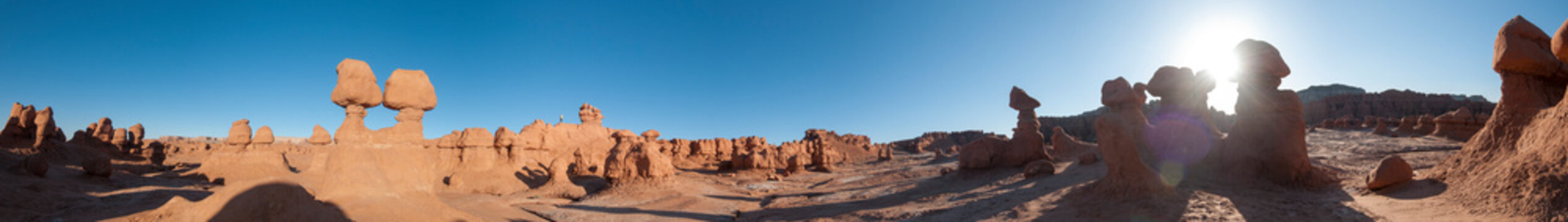 Panorama with tiny person standing on ridge in Goblin Valley State Park near Hanksville, Utah.