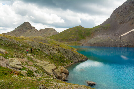 A woman and her daughter hiking past a blue lake, San Juan National Forest,  Silverton, Colorado.