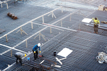 Workers with hard hats on a construction site prepare reinforced concrete for house building	