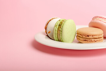 Assorted almond cookies on white round plate on pink background.