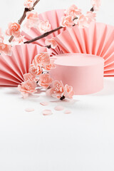 Elegant spring cylinder podium mockup, asian fans, branch of gentle pink sakura flowers in sunlight, shadow in white interior, template for presentation cosmetic products, goods, branding, vertical.