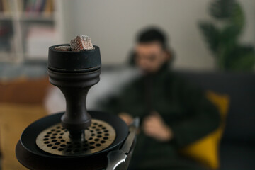 Hookah shisha with glass flask and metal bowl in room with man background and copy space and empty place for text. Traditional Eastern vacation for relaxation