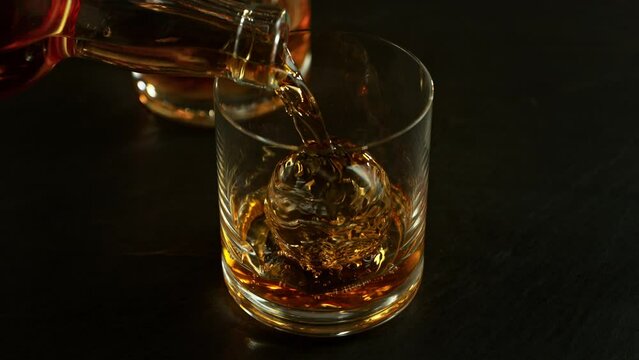 Super Slow Motion Shot of Pouring Whiskey into Glass with Ice Ball at 1000fps with Camera Movement.