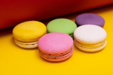 Fototapeta na wymiar Traditional french multicolored macaroons falling on yellow background