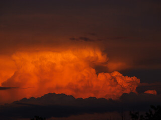 Majestic view of orange glowing cumulonimbus storm cloud forming on summer sky