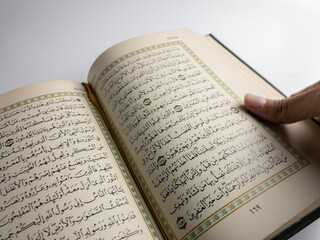 reading al quran and turning page of quran above sajadah (praying mat) isolated on white space. selected focus