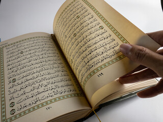 reading al quran and turning page of quran above sajadah (praying mat) isolated on white space. selected focus