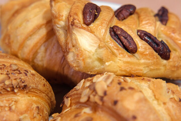 French puff pastry and croissant with toppings. Freshly baked sweet buns couple flaky pastry with almond nuts in a white plate for dessert. Delicious Breakfast or brunch concept. Burekas, turnovers.