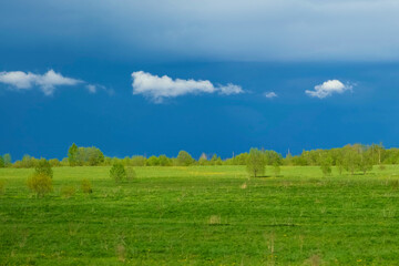 Thunderstorm and Green Meadow. Gray Dark Moody Sky Before the Storm over Grass Field. Rural Landscape. Stormy Dramatic Clouds at Summer Day. Peaceful and tranquil background. Beauty in nature.