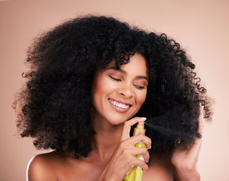 Model, happy or afro hair spray on isolated studio background in frizz control, curly management or oil treatment. Black woman smile, face or natural haircare product for grooming or texture wellness
