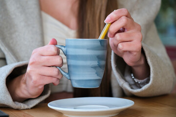 Unrecognizable woman drinking coffee in a cafeteria.