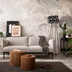 Interior design of industrial living room interior with mock up poster frame, gray sofa, round wooden coffee table, brown leather armchair, black desk, modern lamp, accessories. Home decor. Template.