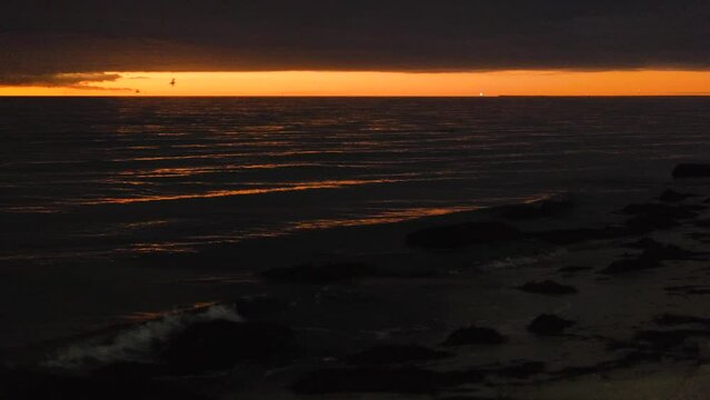 Waves Roll onto Beach with Sunset Reflection on Water Waves on Coast at Sunset 