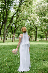 Obraz na płótnie Canvas young beautiful wedding bride walks on nature in the park in a beautiful dress
