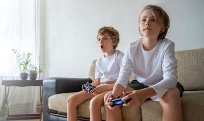 Addicted children playing video game playstation joystick controller at home. Harm of online gadget...