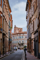 Fototapeta na wymiar Beautiful facades with bricks in Perchepinte street and the Saint Etienne cathedral bell tower in Toulouse old town, in the south of France (Haute Garonne)