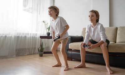 Funny caucasian siblings passionately playing video games in front of tv, two brother sister expressing emotions while enjoying their hobby playstation joystick. Copy space