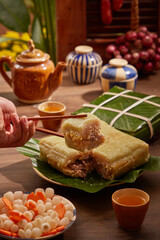 Hand holding a piece of sticky rice cake (Chung cake) on tray Tet, background for holiday food advertising. Front view. Traditional lunar new year food