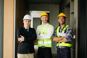 Architect caucasian man working with colleagues mixed race in the construction site. Architecture engineering on big project. Building in construction process interior. look at camera.