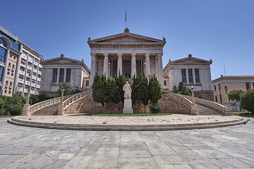Fototapeta na wymiar The old National Library white marble front, with impressive double stairs, doric rhythm columns and the statue of the great donor Valianos. Cultural travel to Athens, Greece.