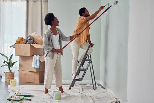 Painting, teamwork or black couple home renovation, diy or house remodel together with paintbrush or roller. Happy smile, woman and African man love working on wall with partnership or collaboration