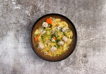 Homemade Meatballs noodle soup in a bowl on a dark background. Top view, flat lay