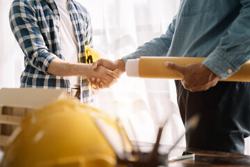 Construction workers, engineers shake hands while working for teamwork and cooperation after completing an agreement in an office facility, successful cooperation concept.