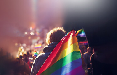 LGBT flag holding with group of people in the background - 574234334
