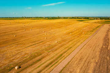 Fototapeta na wymiar Harvested wheat field with straw bales. Drone view