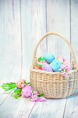 Easter, wicker basket with Easter eggs on a light wooden background. High quality photo
