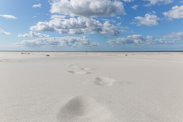Tiefe Perspektive der menschlichen Fußspuren an einem weißen Sandstrand im Sommer