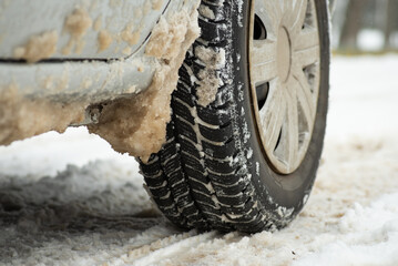 Traffic on winter road after heavy snow. Close up of winter tire on the car on snowy road in town