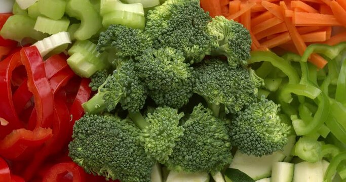Ingredients for stir fry vegetables: broccoli, carrot, corrugate, celeriac, red and green pepper. Spin, seamless loop.