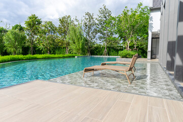 Wooden daybed place on tile floor in swimming pool with blue sky.