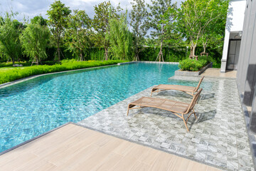 Wooden daybed place on tile floor in swimming pool with blue sky.